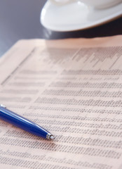 Cup of coffee near newspapers, pen