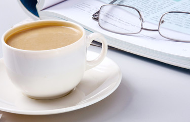 Cup of coffee near the laptop and newspapers