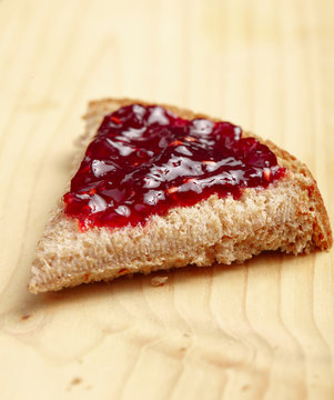 Piece of whole wheat bread with  red raspberry jelly