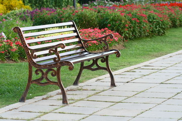 Brown chair in a flowers garden with walkway