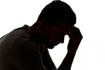Desperate young man in silhouette holding his head