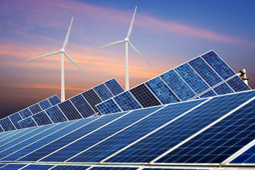 Solar panels and wind turbine against blue sky