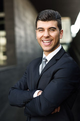 Young businessman near a office building wearing black suit