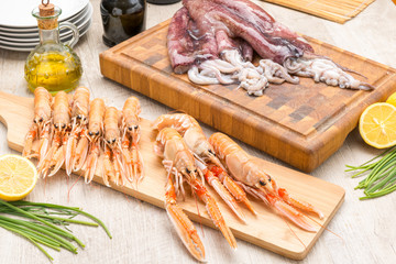Calamari e scampi crudi su taglieri di legno
