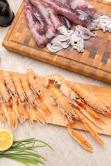 Calamari e scampi crudi su taglieri di legno