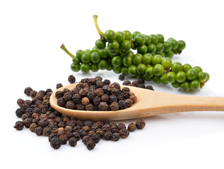 Black pepper in wooden spoon on white background.