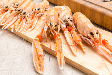 Scampi crudi sul tagliere di legno