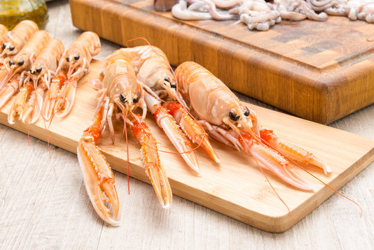 Scampi crudi sul tagliere di legno