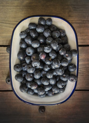 Blueberries in rustic kitchen setting with old wooden background