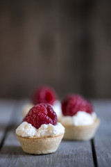 Raspberry tartlets on rustic wooden kitchen  background