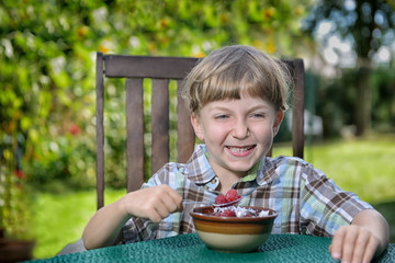 young boy eating a tasty raspberry with yogurt