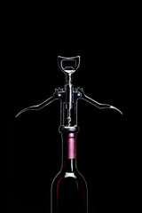 Corkscrew open wine bottle over black background