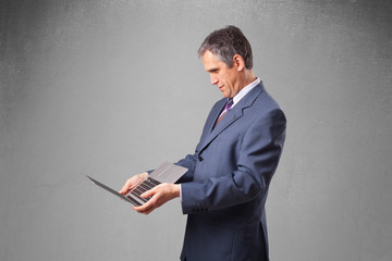 Handsome businessman holding modern laptop
