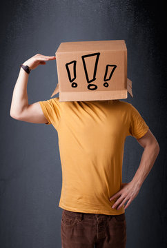 Young man gesturing with a cardboard box on his head with exclam