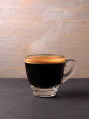 Cup of hot espresso coffee and coffee crop on wood board