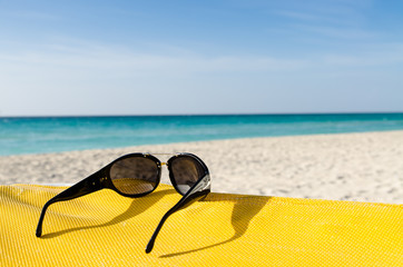 Fototapeta na wymiar Sunglasses on deckchair, seashore