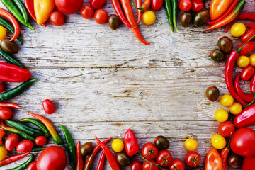 Frame of tomatoes and paprica family varieties over a rustic woo