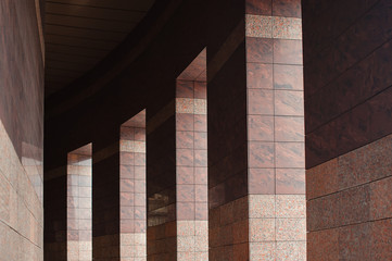 Row of columns with sunlight in the gaps and reflected in shiny