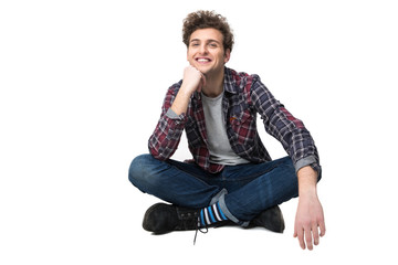 Smiling young man sitting on the floor over white background