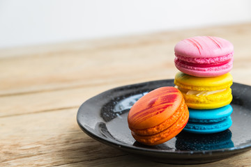 Colorful macaron in black dish on wooden floor