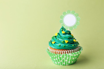 Delicious cupcake with inscription on green background