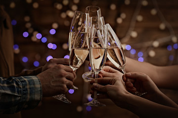 Clinking glasses of champagne in hands on lights background