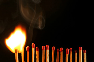 Line of lighted matches on black background