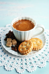 Cup of coffee and tasty cookie on color wooden background