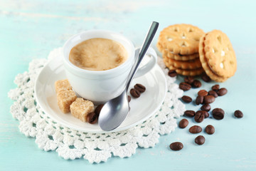 Cup of coffee and tasty cookie on color wooden background