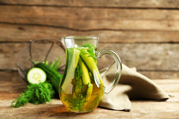 Glass ewer with fresh organic cucumber water on wooden table