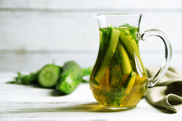 Glass ewer with fresh organic cucumber water on wooden table