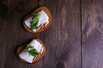 Sandwiches with lard and parsley on wooden background