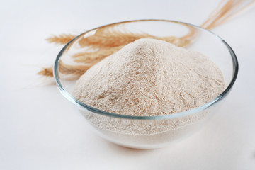 Glass bowl with flour and ears isolated on white