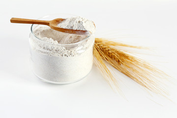 Glass bowl with flour and ears isolated on white