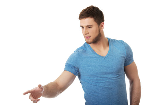 Handsome young man pointing down.