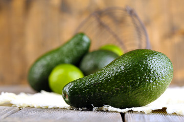Avocado with limes on napkin on wooden background