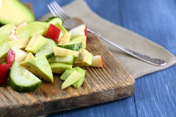 Sliced avocado and apple on cutting board on wooden background
