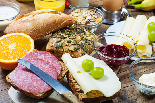 gedeckter Fr&uuml;hst&uuml;ckstisch mit Br&ouml;tchen, K&auml;se, Obst und Marmelade