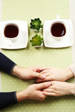 Female and male hands with cups of tea, close-up