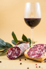 slices of italian salami on bread and some spices and wine