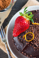serving decorated dark chocolate cake on wooden table
