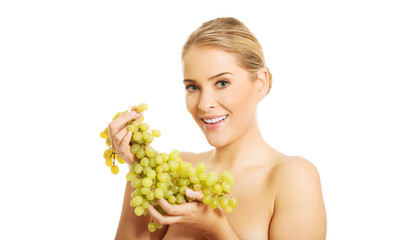 Portrait of nude woman eating grapes,