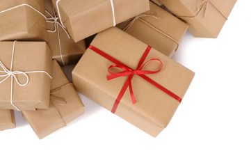 Untidy pile or heap of several lots brown paper wrapped parcel package or gift boxes one unique with red ribbon isolated on white background photo