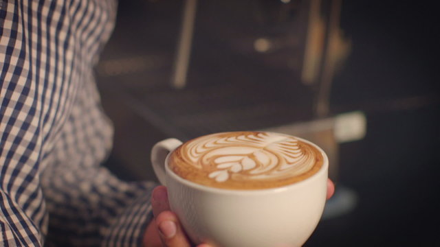Barista puts finishing touch to a cup of freshly prepared latte