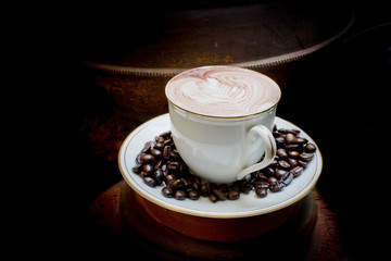 Latte art, coffee in coffee beans and Asian pottery background