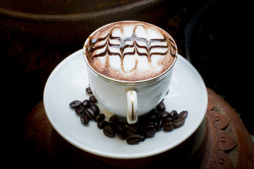 Latte art, coffee in coffee beans and Asian pottery background