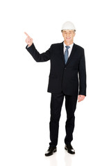 Smiling businessman with hard hat pointing up