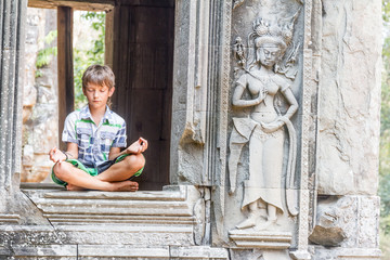 young happy child boy tourist meditating in angkor wat, cambodia