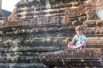 young happy child girl tourist meditating in angkor wat, cambodi