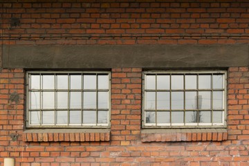 Windows behind bars in an old red brick industrial building